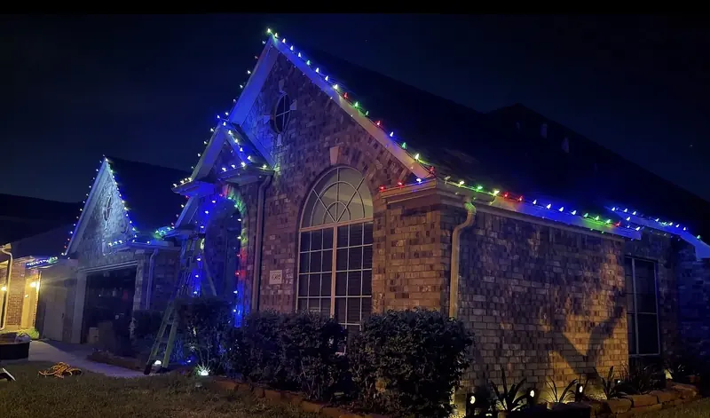 Brick home with colored roofline lighting at night